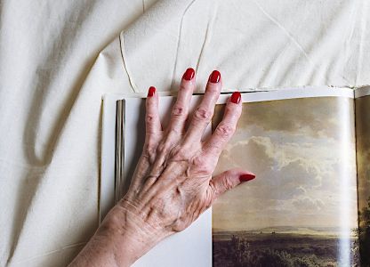 Ältere Hand und Buch auf einem Bettleinen