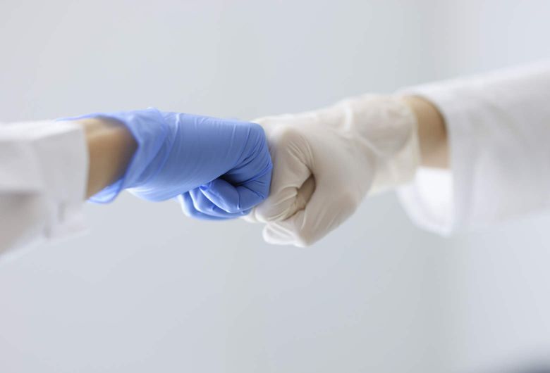 Zwei Hände mit medizinischen Handschuhen